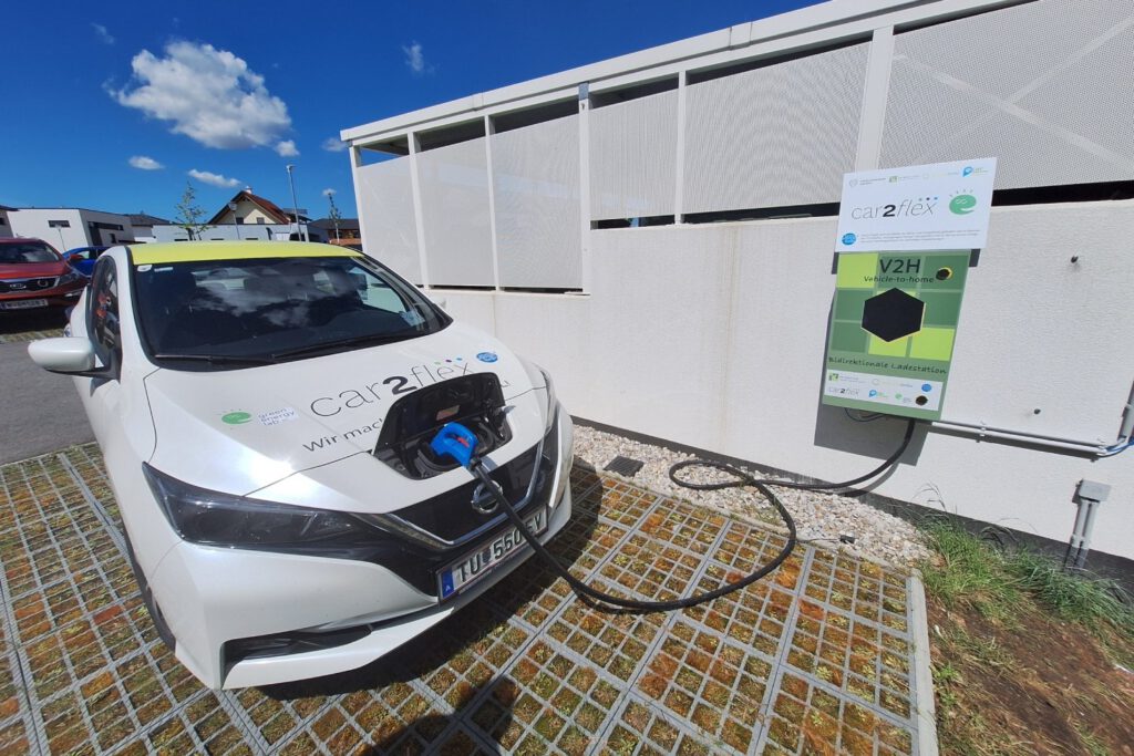 Ein E-Auto ist an einer bidirektionalen Ladesäule angesteckt.