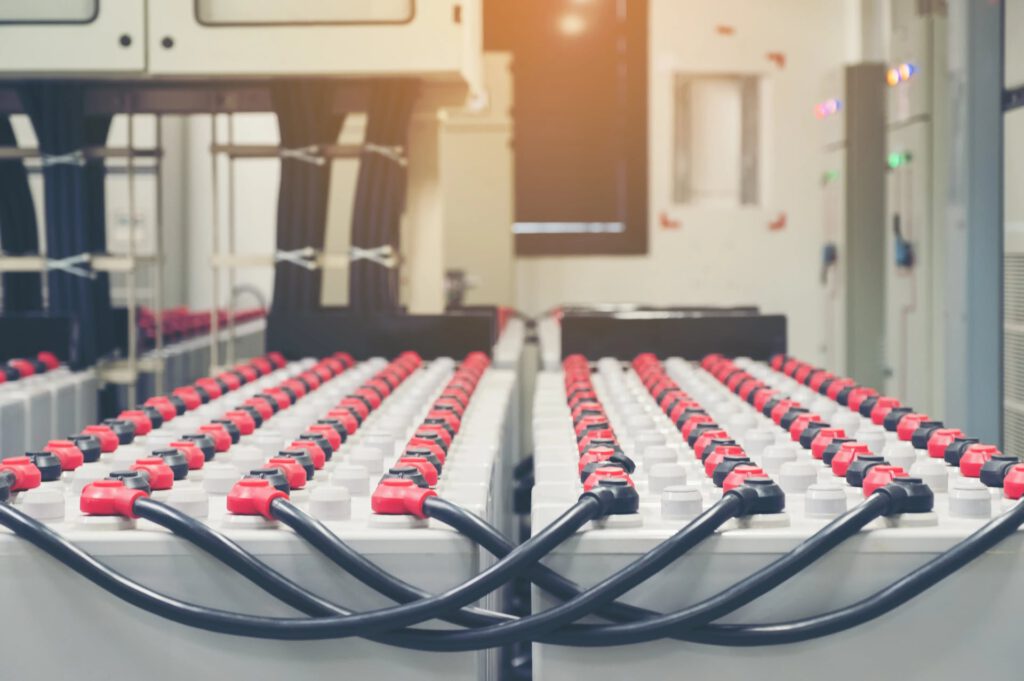 Große Batterien mit roten und schwarzen Kabeln in einem Raum