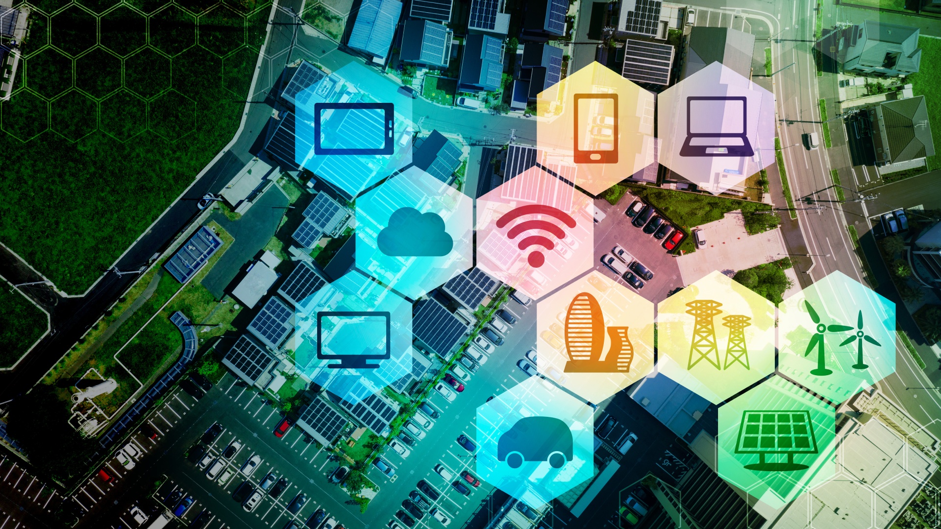 © iStock.com/metamorworks Darstellung einer Stadt im Hintergrund und im Vordergrund werden Icons in Bienenwaben angezeigt (Laptop, Tablet, Smartphone, Bildschirm, WLAN-Zeichen, Windräder, Sonnenkollektor, Fahrzeug, Gebäude, Hochspannungsmast, Wolke)