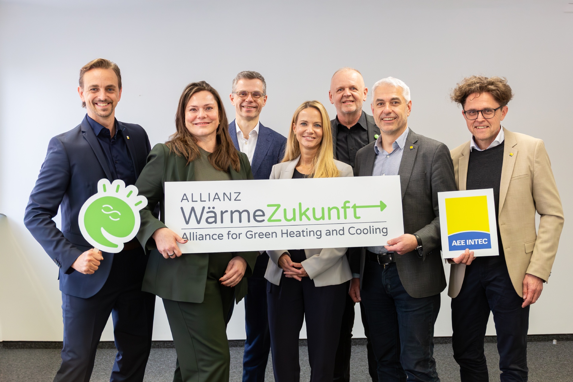 Gruppenfoto von sieben Personen, die drei Schilder mit Logos von Allianz WärmeZukunft, Green Energy Lab und AEE INTEC in der Hand halten